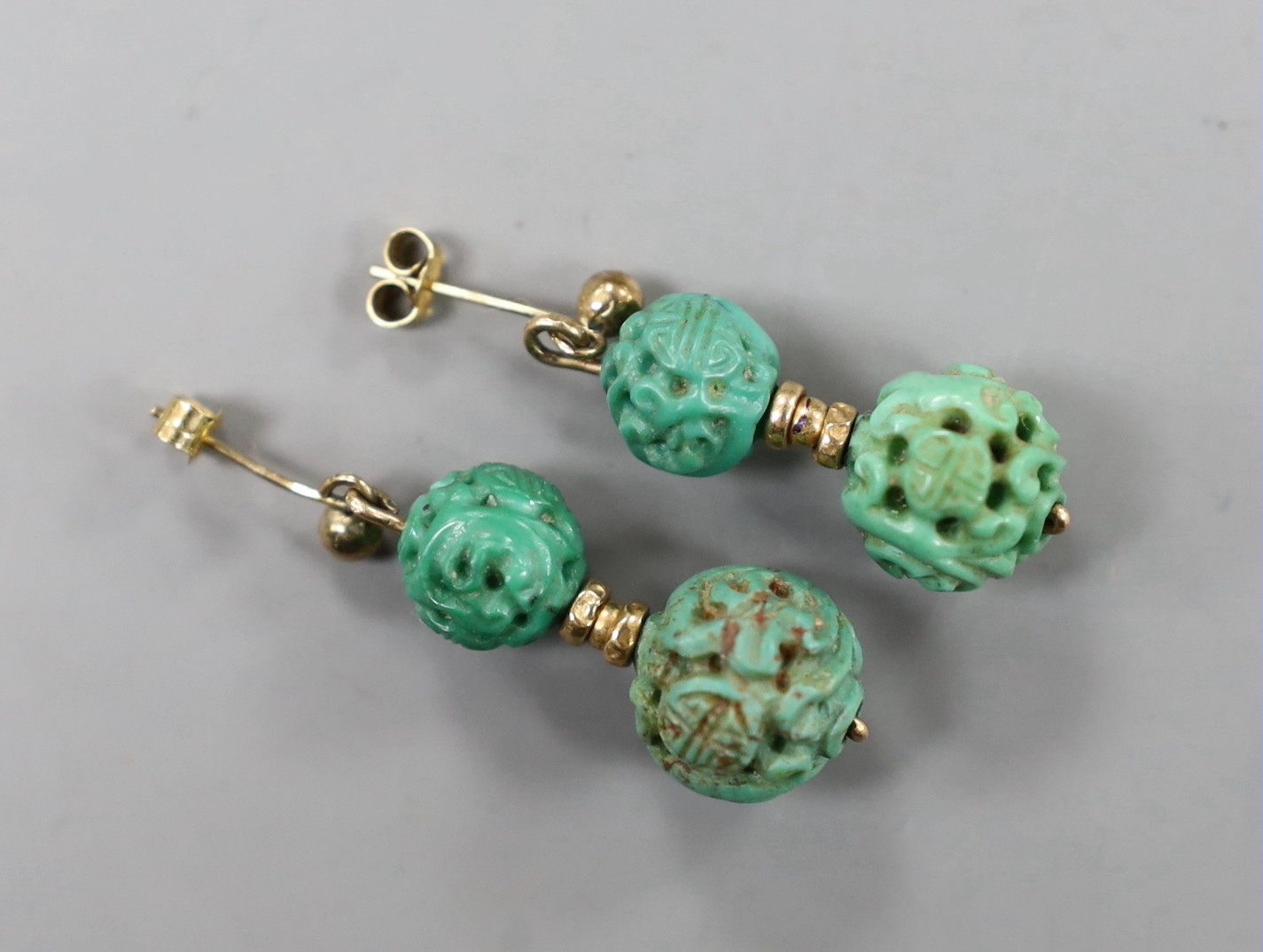 A pair of Chinese yellow metal and two turquoise bead set earrings, both carved with Shou medallions, 25mm, gross weight 5.2 grams.